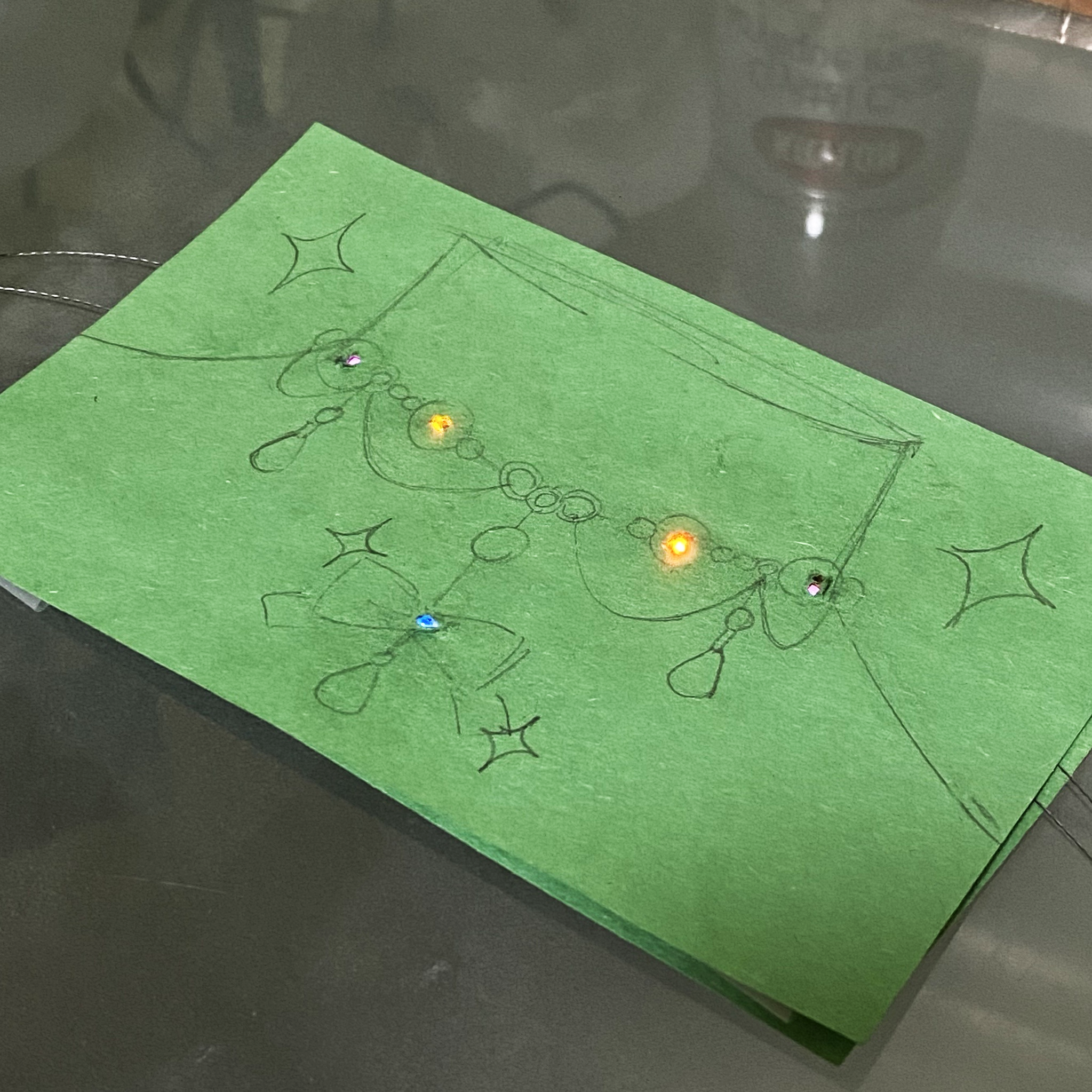 This is the final image, with the drawing placed on top. Holes were poked through the paper to light up the beads in the drawing.