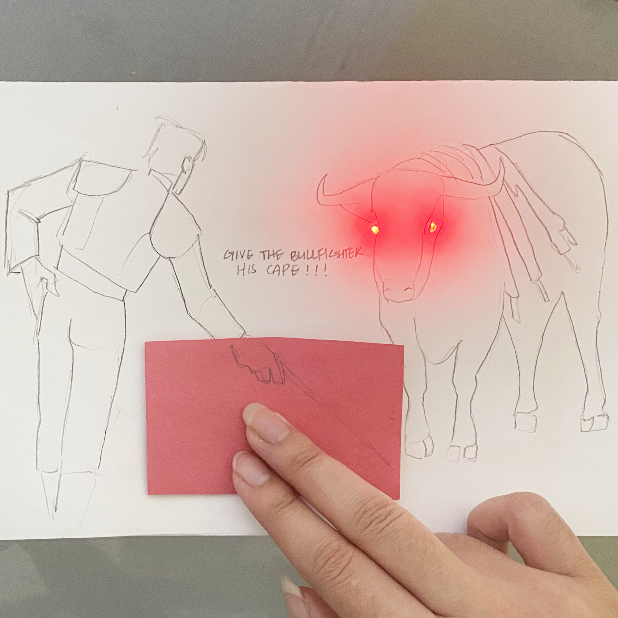 This is a refined version of the previous bullfighting concept. I didn't use the conductive fabric for this, but it is more interactive. The paper prompts us to give the bullfighter his cape, and when you press down, the bull's eyes light up!